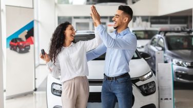 hombre y mujer chocando las manos manifestando alegría por comprar un auto